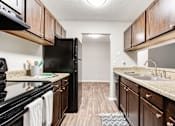 Thumbnail 37 of 81 - a kitchen with black appliances and wooden cabinets at Magnolia Place at Stockbridge Apartments, Georgia, 30281