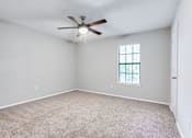 Thumbnail 40 of 81 - an empty living room with a ceiling fan and a window at Magnolia Place at Stockbridge Apartments, Stockbridge