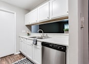 Thumbnail 68 of 81 - a kitchen with a dishwasher and white cabinets at Magnolia Place at Stockbridge Apartments, Stockbridge, GA