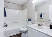 Thumbnail 71 of 81 - a bathroom with a toilet sink and a mirror at Magnolia Place at Stockbridge Apartments, Georgia