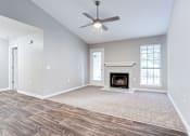 Thumbnail 46 of 81 - an empty living room with a fireplace and a ceiling fan at Magnolia Place at Stockbridge Apartments, Stockbridge, GA