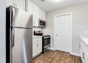 Thumbnail 52 of 81 - a kitchen with stainless steel appliances and white cabinets at Magnolia Place at Stockbridge Apartments, Stockbridge, Georgia