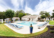Thumbnail 8 of 81 - a swimming pool with lounge chairs around it in front of a house at Magnolia Place at Stockbridge Apartments, Georgia