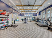 Thumbnail 22 of 39 - a gym with cardio machines and weights on the floor and a window at Century Mundy Mill Apartments, Oakwood