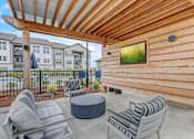 Thumbnail 28 of 39 - a patio with chairs and a table in front of a wooden house at Century Mundy Mill Apartments, Georgia 30566