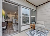 Thumbnail 10 of 39 - a living room with a couch and a door to a kitchen at Century Mundy Mill Apartments, Oakwood, GA 30566