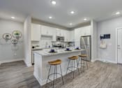 Thumbnail 5 of 39 - a kitchen with a large island with three stools at Century Mundy Mill Apartments, Oakwood, GA