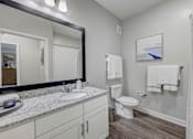 Thumbnail 9 of 39 - a bathroom with a mirror and a toilet and a sink at Century Mundy Mill Apartments, Oakwood