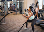 Thumbnail 19 of 39 - a woman in a gym using a resistance rope at Century Mundy Mill Apartments, Oakwood 30566