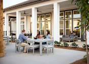 Thumbnail 38 of 39 - a group of people sitting around a table on a patio at Century Mundy Mill Apartments, Oakwood 30566