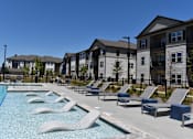 Thumbnail 11 of 39 - a swimming pool with lounge chairs in front of apartment buildings at Century Mundy Mill Apartments, Oakwood