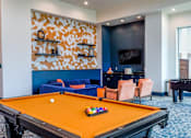 Thumbnail 24 of 36 - A pool table is in the middle of a room with a blue couch and a television.