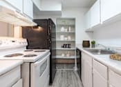 Thumbnail 12 of 18 - A modern kitchen with white appliances and a black refrigerator.