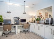 Thumbnail 31 of 31 - A white tiled kitchen with a desk and chairs.