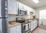 Thumbnail 29 of 31 - A kitchen with white cabinets and a granite countertop.