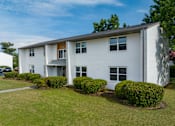 Thumbnail 33 of 34 - a white apartment building with a green lawn and bushes in front of it at Summit Augusta, Augusta