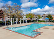 Thumbnail 26 of 31 - A large swimming pool surrounded by a white fence and trees.