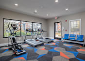 Thumbnail 22 of 31 - A gym with treadmills, elliptical machines, and a bench.
