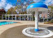 Thumbnail 13 of 31 - A blue and white water fountain in the middle of a pool area.