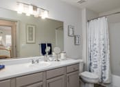 Thumbnail 30 of 31 - A bathroom with a white sink, toilet, and a shower curtain.