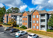 Thumbnail 15 of 31 - A parking lot in front of a brick apartment building.