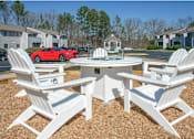 Thumbnail 6 of 30 - a patio with a table and chairs and a red car parked in a parking lot