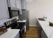 Thumbnail 4 of 21 - A kitchen with black appliances and white cabinets.