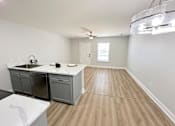 Thumbnail 1 of 21 - A kitchen with a white countertop and wooden flooring.