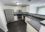 Thumbnail 19 of 19 - A kitchen with a stainless steel refrigerator, microwave, oven, and sink.