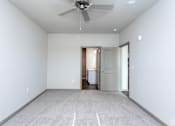 Thumbnail 4 of 27 - a bedroom with white walls and a ceiling fan