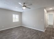 Thumbnail 10 of 34 - A room with a ceiling fan and wooden flooring.