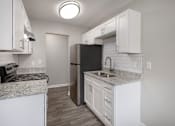 Thumbnail 8 of 34 - A kitchen with white cabinets and a black refrigerator.