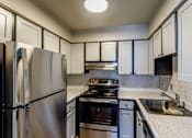 Thumbnail 14 of 30 - A kitchen with a stainless steel refrigerator and black stove top oven.