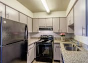 Thumbnail 7 of 30 - A kitchen with a black refrigerator and stove top oven.