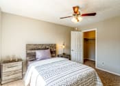 Thumbnail 16 of 30 - A bedroom with a bed, nightstand, and a ceiling fan.