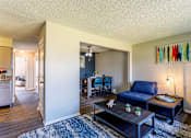 Thumbnail 12 of 30 - A living room with a blue couch and a coffee table.