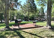 Thumbnail 12 of 27 - a park with a grill and trees and a building