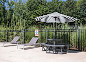 Thumbnail 24 of 27 - a patio with two chairs and a table with an umbrella