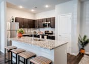 Thumbnail 1 of 31 - A kitchen with a granite countertop and bar stools.