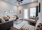 Thumbnail 2 of 31 - A living room with a grey couch, a coffee table, and a television.