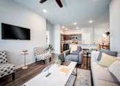 Thumbnail 21 of 31 - A living room with a television, couches, and a dining table.