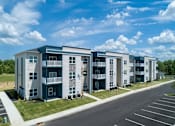 Thumbnail 28 of 31 - A row of modern apartment buildings with a parking lot in front.