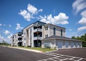 Thumbnail 29 of 31 - A modern apartment building with a parking lot in front.