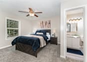 Thumbnail 5 of 23 - A bedroom with a bed, nightstand, and a ceiling fan.