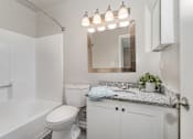 Thumbnail 8 of 23 - A white bathroom with a toilet, sink, and mirror.