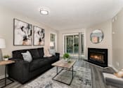 Thumbnail 1 of 23 - A modern living room with a black couch, a fireplace, and a painting on the wall.