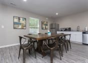Thumbnail 7 of 19 - a dining area with a table and chairs and a kitchen with a refrigerator and sink