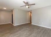 Thumbnail 17 of 19 - an empty living room with a ceiling fan and wood floors