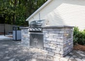 Thumbnail 10 of 19 - a stone outdoor kitchen with a grill on a patio