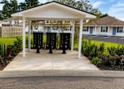 Thumbnail 9 of 21 - A white pavilion with a black pole in front of a building.